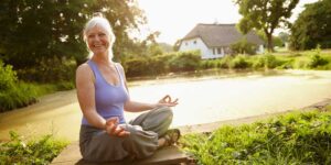 Attractive mature woman meditating in a garden at sunset, meditation-changes-appearance