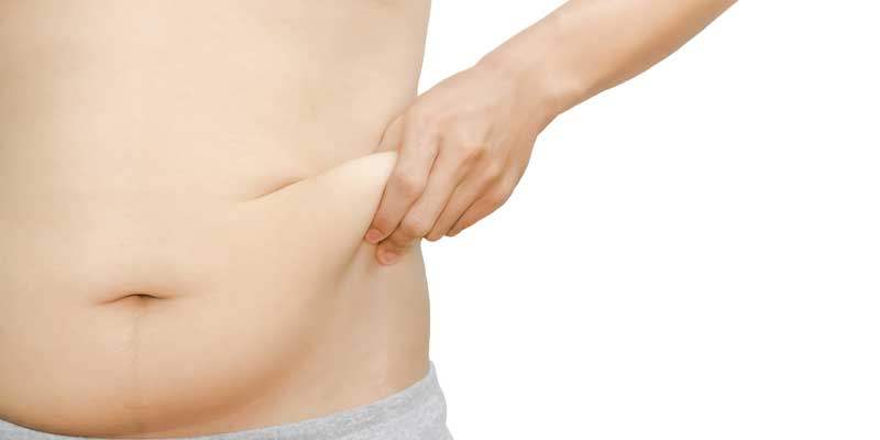 man pinching his love handles to show unwanted body fat