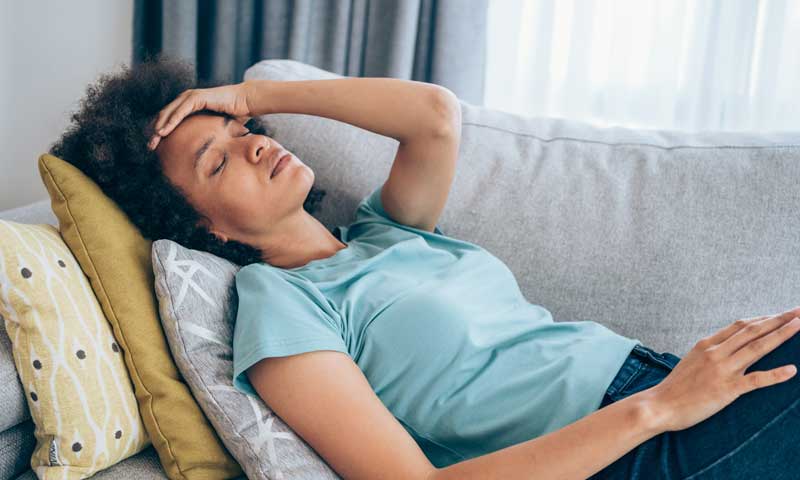 A woman lying on the couch looking very fatigued