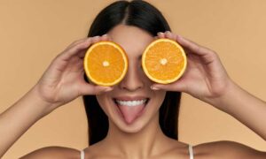 Young woman playfully covering her eyes with orange slices.