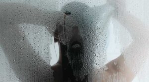 Silhouette of woman washing hair in the shower