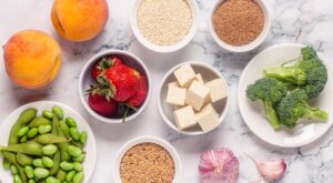 Dishes of phytoestrogen-rich foods on a countertop including strawberries, tofu, soybeans, and broccoli