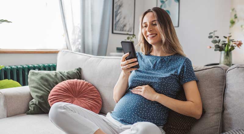 A pregnant woman sitting on a couch in her home