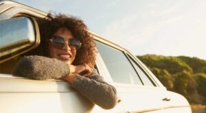 A woman wearing sunglasses leaning out of a car window