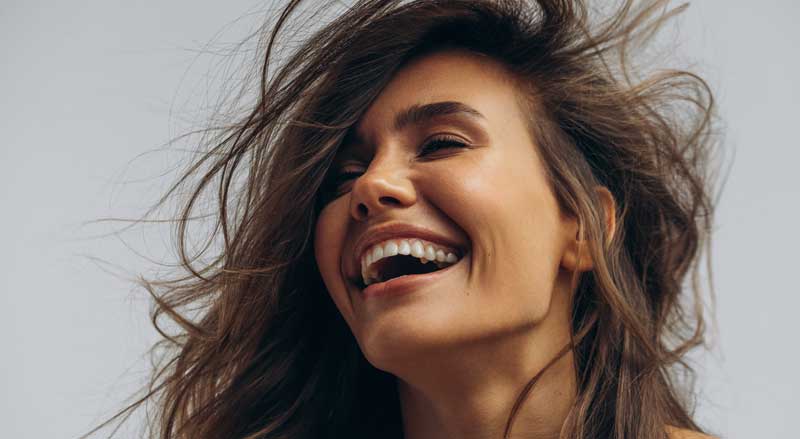A smiling happy woman with long windblown brown hair