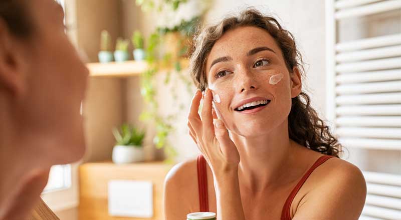 A woman applying moisturizer to her face