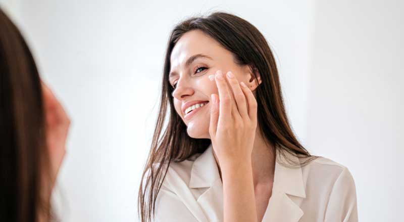 A woman applying moisturizer to face