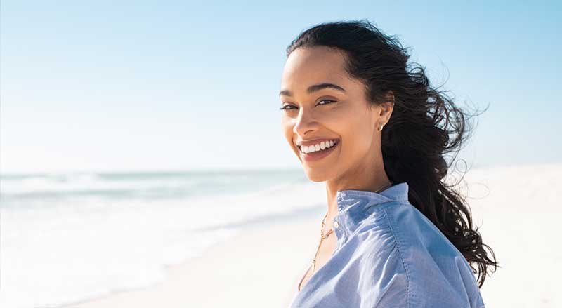 A smiling woman stands at the shore