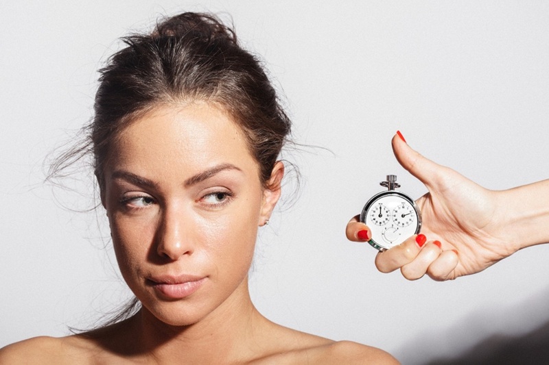 A woman looks sideways at a watch near her face, symbolizing the importance of timing in understanding skin types