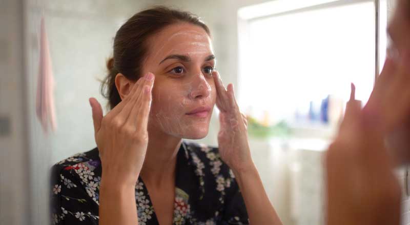 A woman looking in a mirror with soap on her face